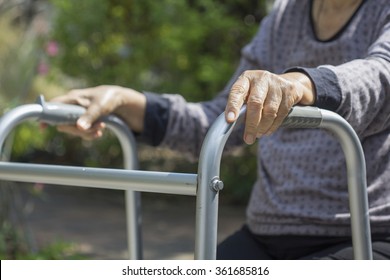 Elderly sitting in backyard with walker.