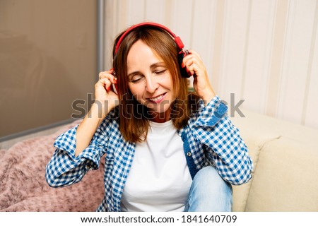 Elderly smiling female in headphones listening to music. She is buying it in appstore on cyber monday. Woman closes her eyes cause she like this music and lifestyle