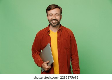 Elderly smiling fun cheerful happy cool IT man 40s years old he wears casual clothes red shirt t-shirt hold closed laptop pc computer isolated on plain pastel light green background studio portrait - Powered by Shutterstock