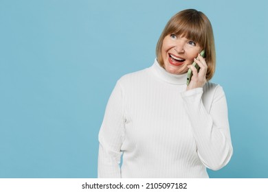 Elderly Smiling Happy Grandmother Caucasian Woman 50s Wearing White Knitted Sweater Talk Speak On Mobile Cell Phone Isolated On Plain Blue Color Background Studio Portrait. People Lifestyle Concept