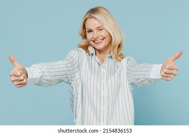 Elderly Smiling Satisfied Happy Caucasian Woman 50s Wear Striped Shirt Show Thumb Up Like Gesture Blink Isolated On Plain Pastel Light Blue Color Background Studio Portrait. People Lifestyle Concept