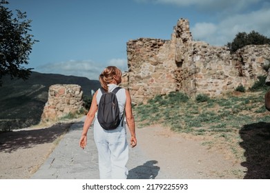 Elderly Smiling Senior Traveling Mature Woman Backpacker Tourist Walking Posing Outdoors In Ancient Europe Fortress Ruins. Retired People Summer Holiday Vacation, Active Lifestyle Concept