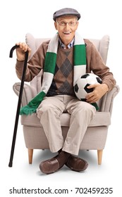 Elderly Soccer Fan With A Football And A Scarf Sitting In An Armchair Isolated On White Background