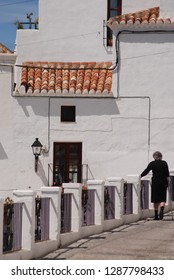 Elderly Spanish Woman In Black Walking In White Village Street. Mijas, Andalusia