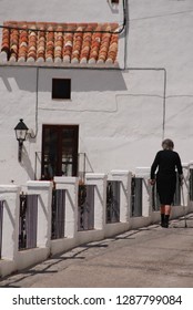 Elderly Spanish Woman In Black Walking In White Village Street. Mijas, Andalusia