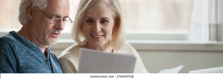 Elderly spouses read paper from bank, analyzing financial statement manage together family budget feels satisfied, enough money, taxes refund concept. Horizontal photo banner for website header design