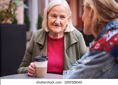 Elderly stylish woman drinking coffee at the street cafe and having pleasure conversation with her lovely daughter. Stock photo - Powered by Shutterstock