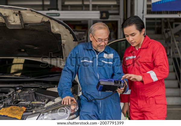 Elderly vehicle mechanic use an obd2 car\
diagnostics device scanner to interpreting automotive error codes.\
Senior professional mechanic maintenance the engine in garage\
workshop. Auto repair\
service
