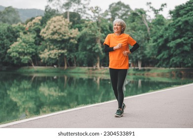 Elderly, white-haired Asian woman exercising in the park early in the morning. - Powered by Shutterstock