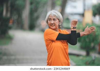 Elderly, white-haired Asian woman exercising in the park early in the morning. - Powered by Shutterstock