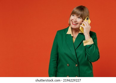 Elderly woman 50s in green classic suit talk speak on mobile cell phone conducting pleasant conversation isolated on plain orange color background studio portrait. People business lifestyle concept - Powered by Shutterstock