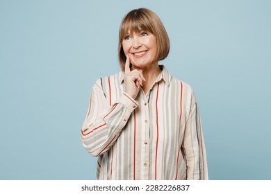 Elderly woman 50s years old wear light striped shirt put hand prop up on chin, lost in thought and conjectures isolated on plain pastel blue cyan color background studio portrait. Lifestyle concept - Shutterstock ID 2282226837