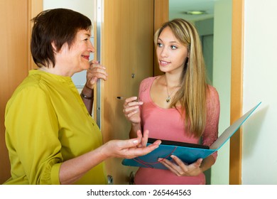 Elderly Woman Answers The Questions Of Young Employee  In Door At Home