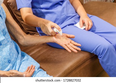 Elderly woman applying hand sanitizer gel from caregiver to helping protect from coronavirus covid-19 - Powered by Shutterstock