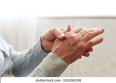 Elderly Woman Applying Moisturizing Lotion Cream On Hand Palm, Easing Aches. Senior Old Lady Experiencing Severe Arthritis Rheumatics Pains, Massaging, Warming Up Arm. Close Up, Copy Space, Background