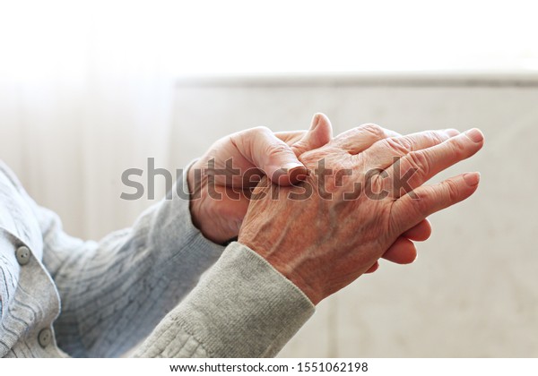 Elderly woman applying moisturizing lotion
cream on hand palm, easing aches. Senior old lady experiencing
severe arthritis rheumatics pains, massaging, warming up arm. Close
up, copy space,
background