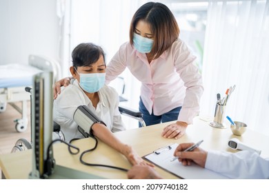 An Elderly Woman And An Asian Woman Come To See The Doctor For A Check-up At The Hospital. Blood Pressure Is Being Checked. Wear A Mask. The Idea Is To Take Care Of Elderly Patients.