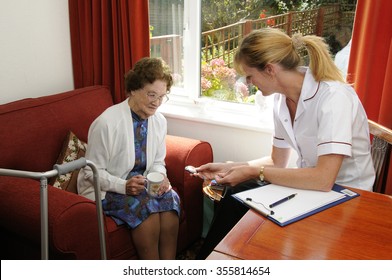 An Elderly Woman Being Given Instruction On The Use Of An Emergency Push Button Medical Assistance Device By A Health Worker. 'The Old Lady Is Deceased And Is My Mother'