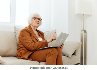 An Elderly Woman In A Brown Suit Is Sitting With A Laptop Holding A Video Conference From Home Sharing Her Valuable Opinion With Colleagues