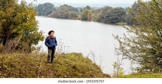 Elderly Woman By The River In Autumn While Walking