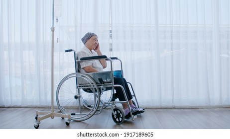 An elderly woman with cancer sits in a wheelchair and she has a headache while being hospitalized. - Powered by Shutterstock