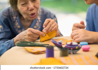 Elderly Woman With Caregiver In The Needle Crafts Occupational Therapy  For Alzheimer’s Or Dementia