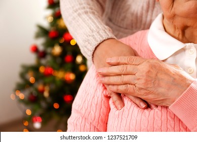 Elderly Woman Celebrating Christmas At Home, With Decorated Holiday Pine Tree On Background. Old Lady At Nursing Home. Close Up, Copy Space, Cropped Shot.