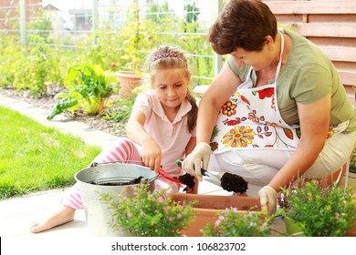 Elderly Woman And Child Replanting Flowers For Better Growth