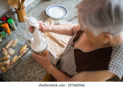 Elderly Woman Cooking In The Kitchen At Home