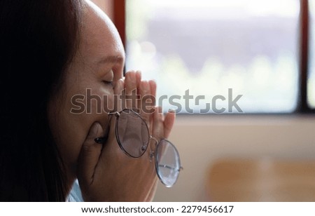 Elderly woman crying wipes tears with hands feels unhappy, bad news. Middle-aged woman taking off glasses closed eyes rubbing eyelid suffers from eye strain deterioration eyesight with age concept