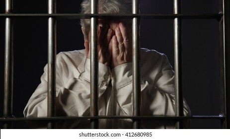 Elderly Woman In Dark Prison Behind Bars Of The Jail