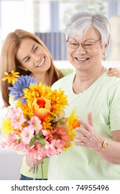 Elderly Woman And Daughter Smiling Happily At Mother's Day, Having Flowers.?