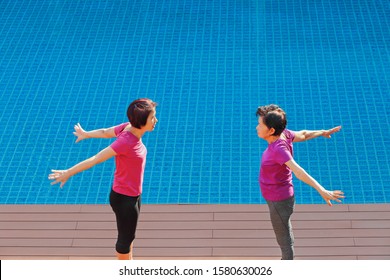 Elderly Woman Doing Exercise With Daughter At Pool Patio