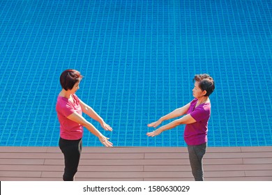 Elderly Woman Doing Exercise With Daughter At Pool Patio