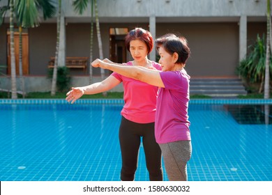 Elderly Woman Doing Exercise With Daughter At Pool Patio