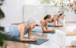 Elderly Woman Doing Pilates Exercises In Group In Fitness Studio