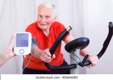 Elderly Woman Doing Sport Effort On A Spinning Bike Having Hear Hart Rate And Blood Pressure Monitored.