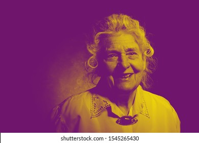 Elderly Woman Dressed In A Blouse With Embroidery And An Amber Vintage Brooch. She Looks Like A Professor, Doctor Or Scientist. Dignity, Confidence, Wisdom, Artistic  Image With Surreal Color