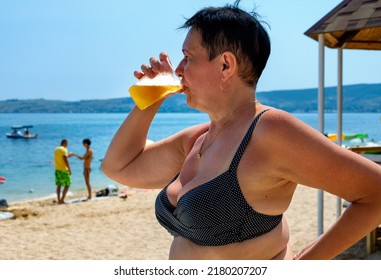 Elderly Woman Drinking Beer On The Beach. Sunny Day, Summer.