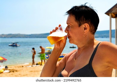 Elderly Woman Drinking Beer On The Beach. Sunny Day, Summer.