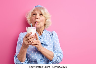 Elderly Woman Drinking Milk Cocktail Isolated Over Pink Background, Portrait. People, Lifestyle Concept