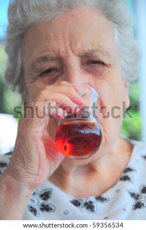 an elderly woman drinks tea