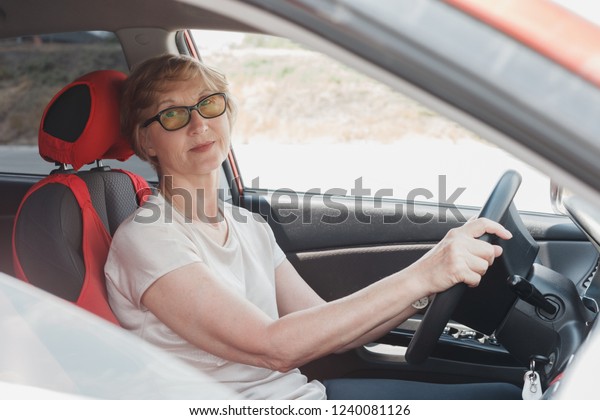 The elderly woman\
drives the car. Close up