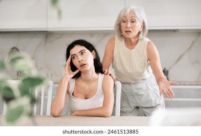 Elderly woman during family quarrel with young woman in kitchen at home - Powered by Shutterstock