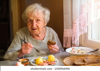 Elderly Woman Eat Sitting At Dinner Table At Home.