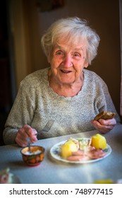 An elderly woman eating lunch sitting at the table.