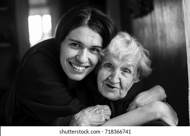 Elderly Woman In An Embrace With His Adult Daughter. Black And White Portrait.