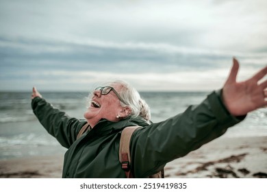 Elderly woman enjoying freedom on a beach with open arms - Powered by Shutterstock