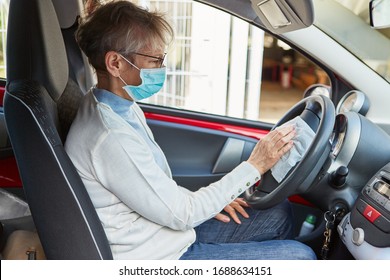 Elderly Woman With Face Mask In Car Sharing Rental Car During Steering Wheel Disinfection Due To Corona Virus