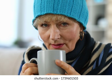 Elderly woman feels sick and drinks tea at home. Lady in knitted hat takes cup tea. Parents do not tolerate loneliness, suffer from complications. Chronic diseases, frequent concomitant aging - Shutterstock ID 1739601503